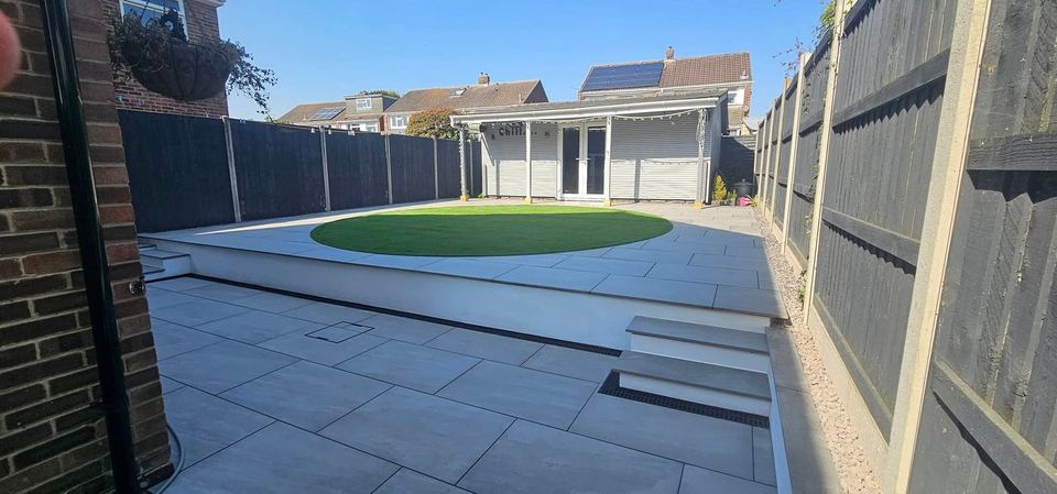 Raised porcelain patio with steps and a circular artificial lawn