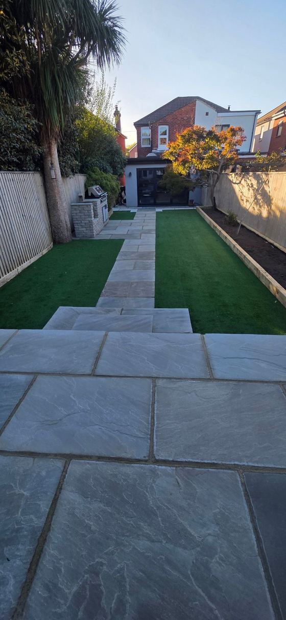 Sandstone patio with steps, stone path, artificial lawn and outdoor kitchen