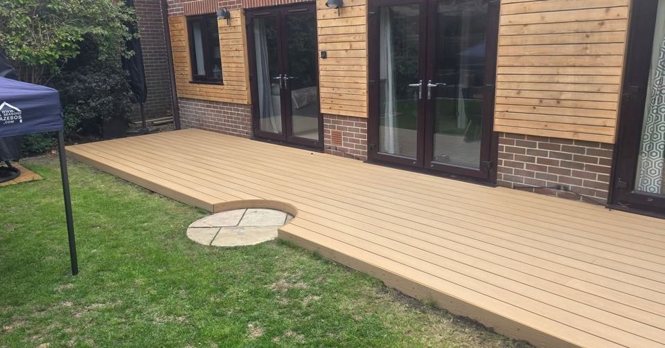Composite decking with a circular paved feature by the patio doors