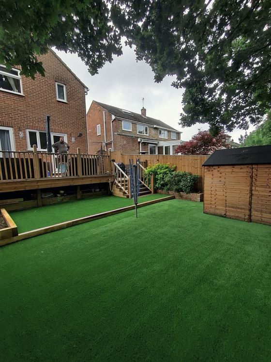 Artificial lawn with sleeper edging, a raised deck and a shed
